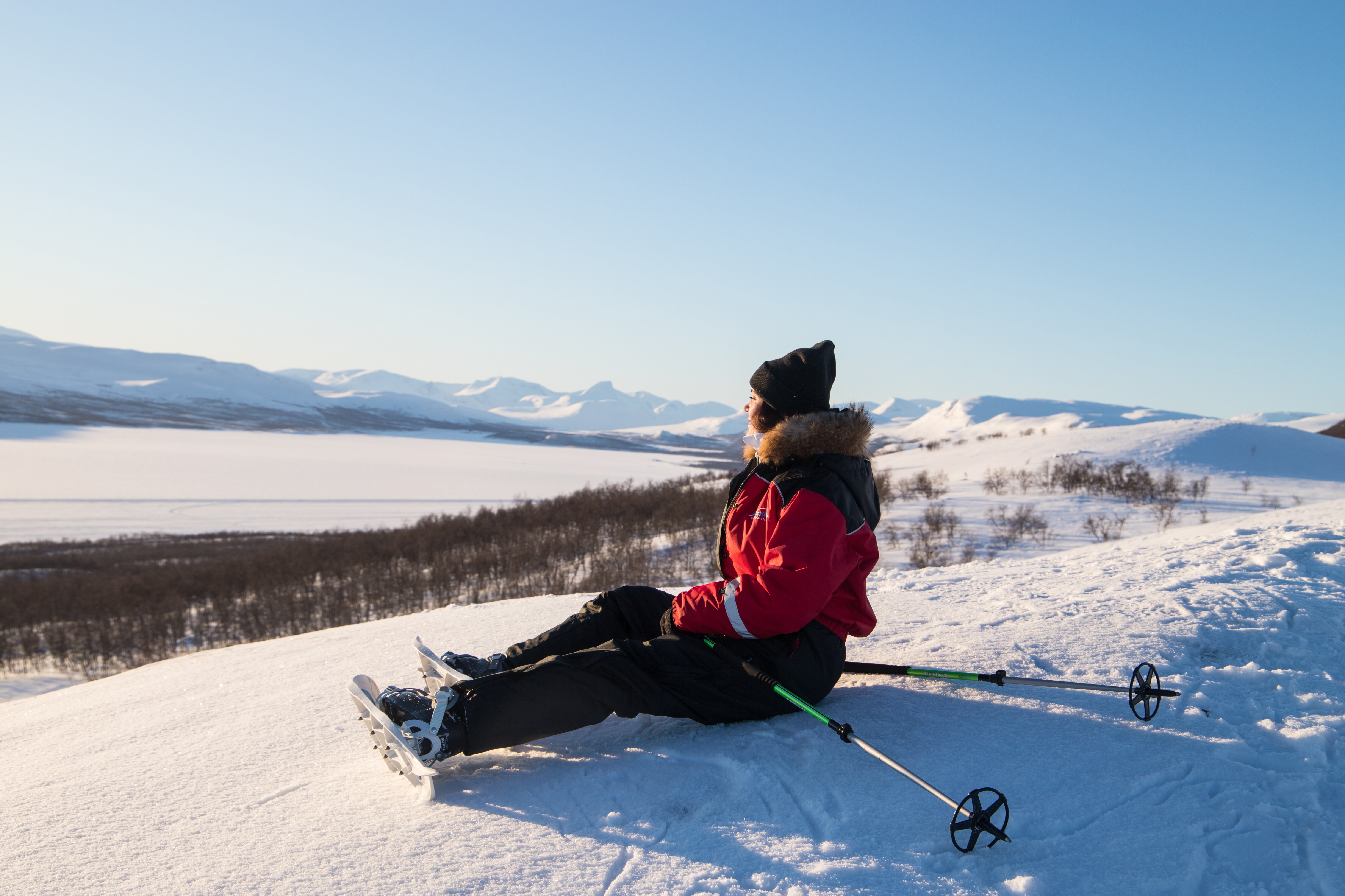 A woman on snowshoes gazes out across a vast frozen landscape in Kilpisjarvi