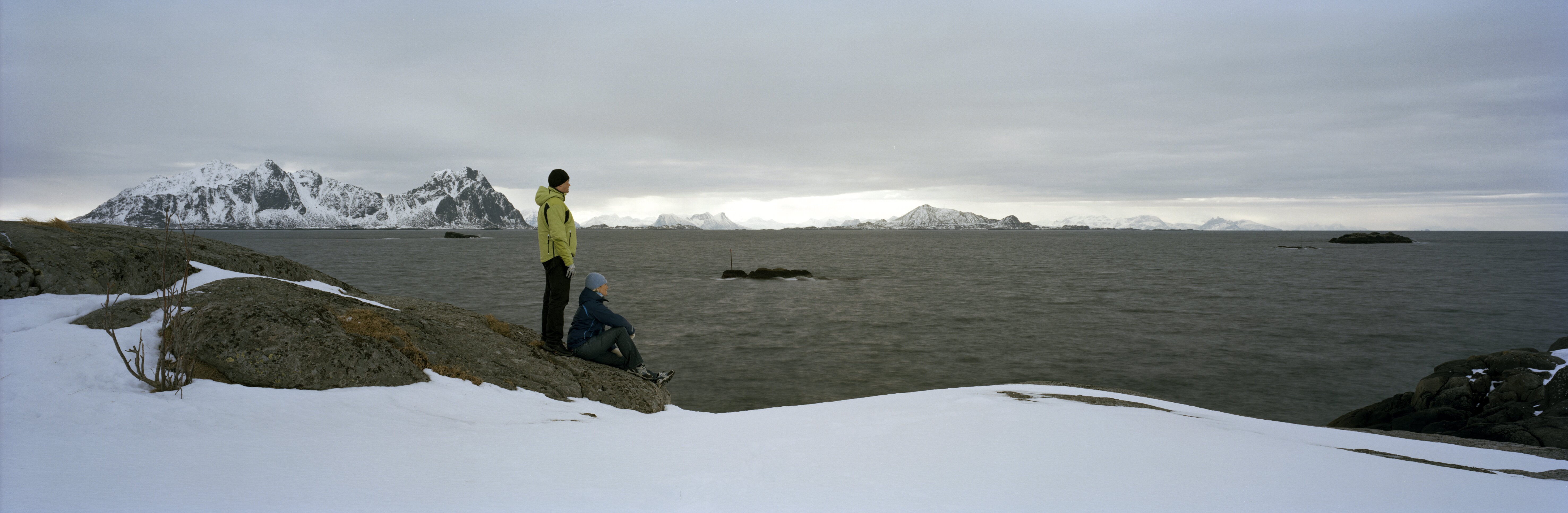 A couple on the shoreline of Norway looking across the water