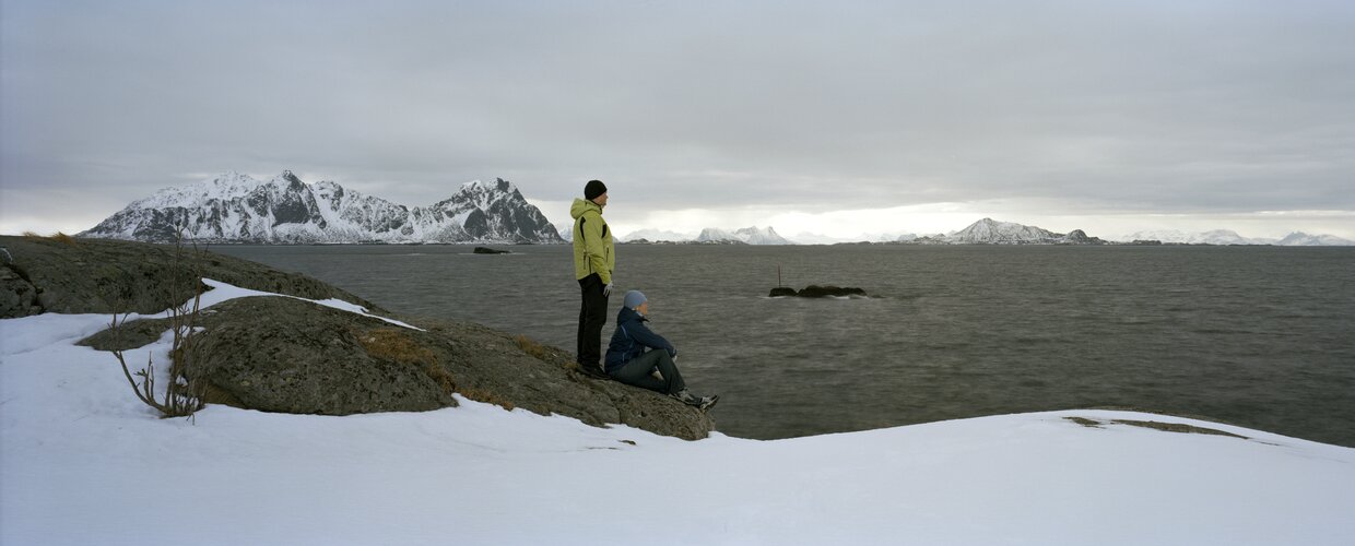 A couple on the shoreline of Norway looking across the water