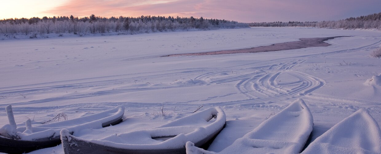 The frozen river Muonio in Karesuando with snow-covered canoes