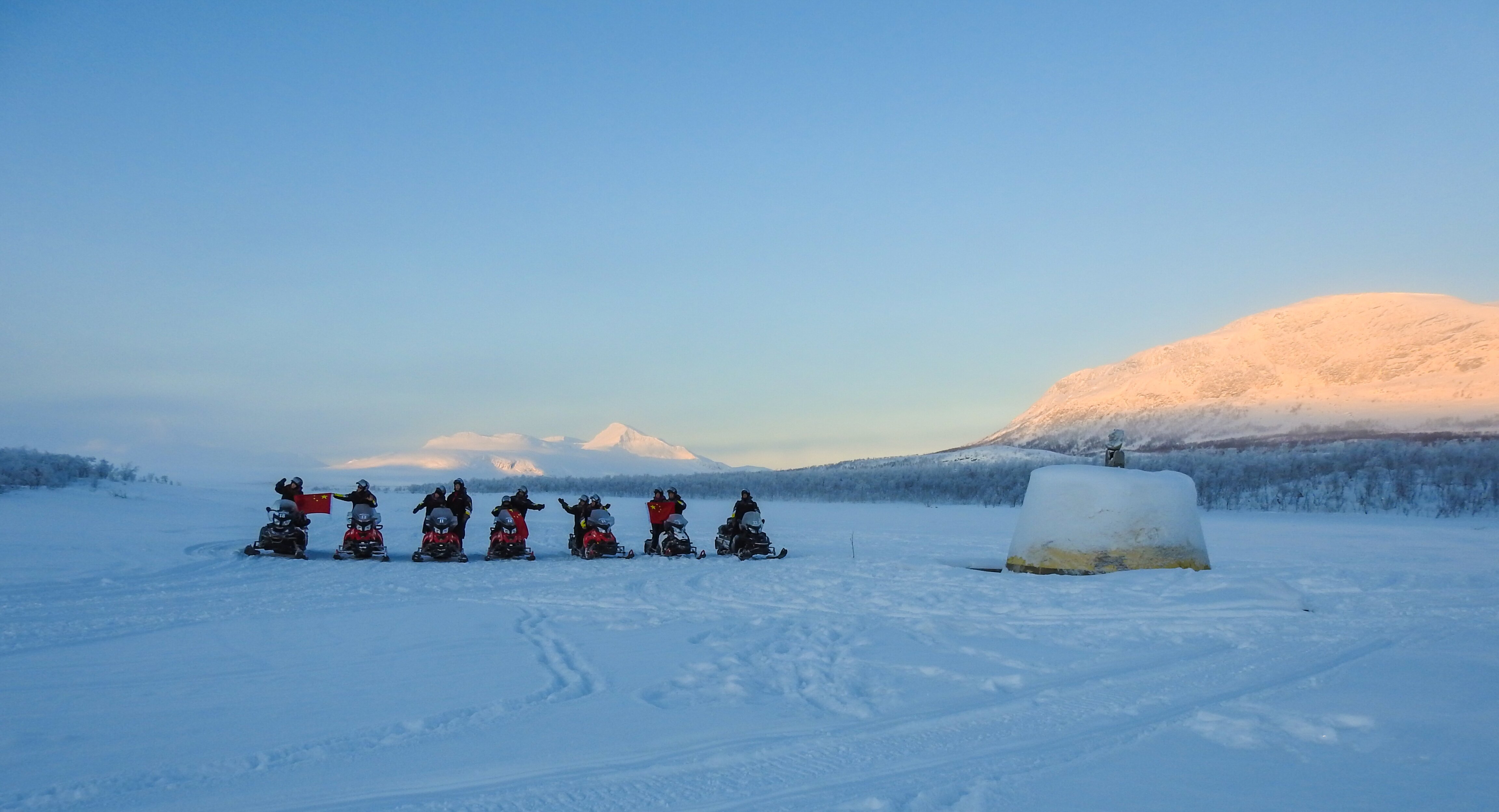 A group of snowmobilers circling the Three-Country Cairn in northwesternmost Finland