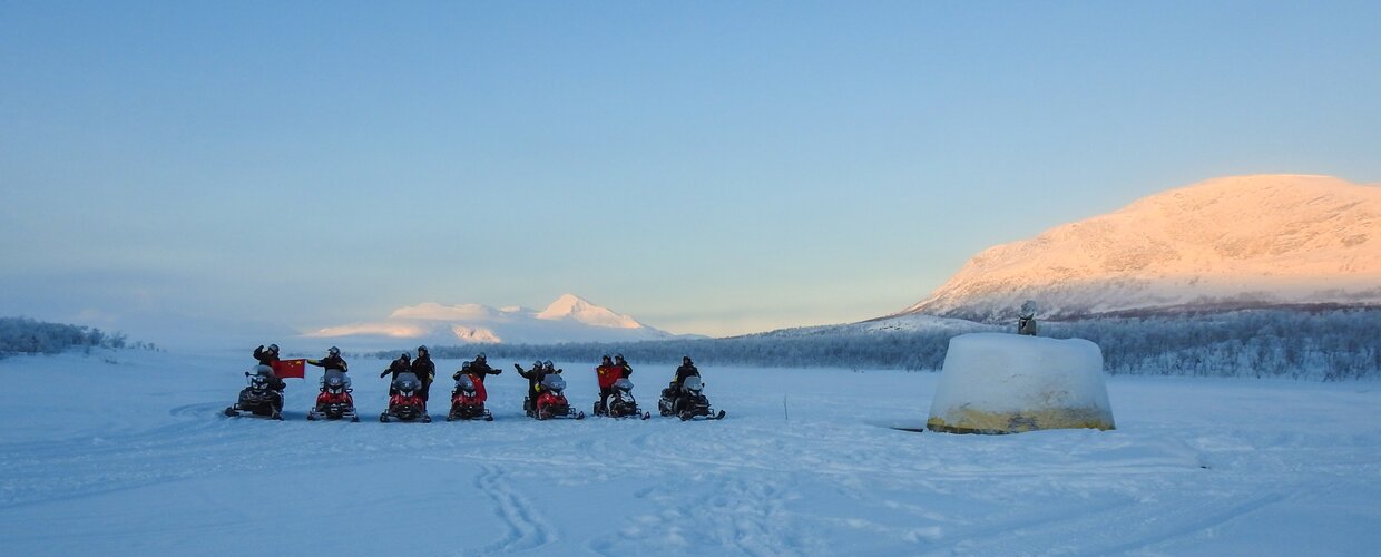 A group of snowmobilers circling the Three-Country Cairn in northwesternmost Finland